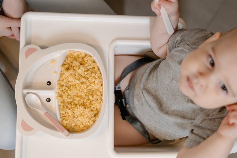 Bébé dans sa chaise haute avec son coffret repas — cadeau de naissance pratique