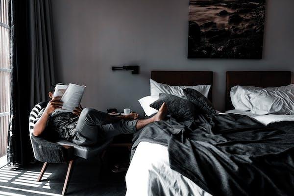 Homme qui lit le journal avec les pieds sur le lit